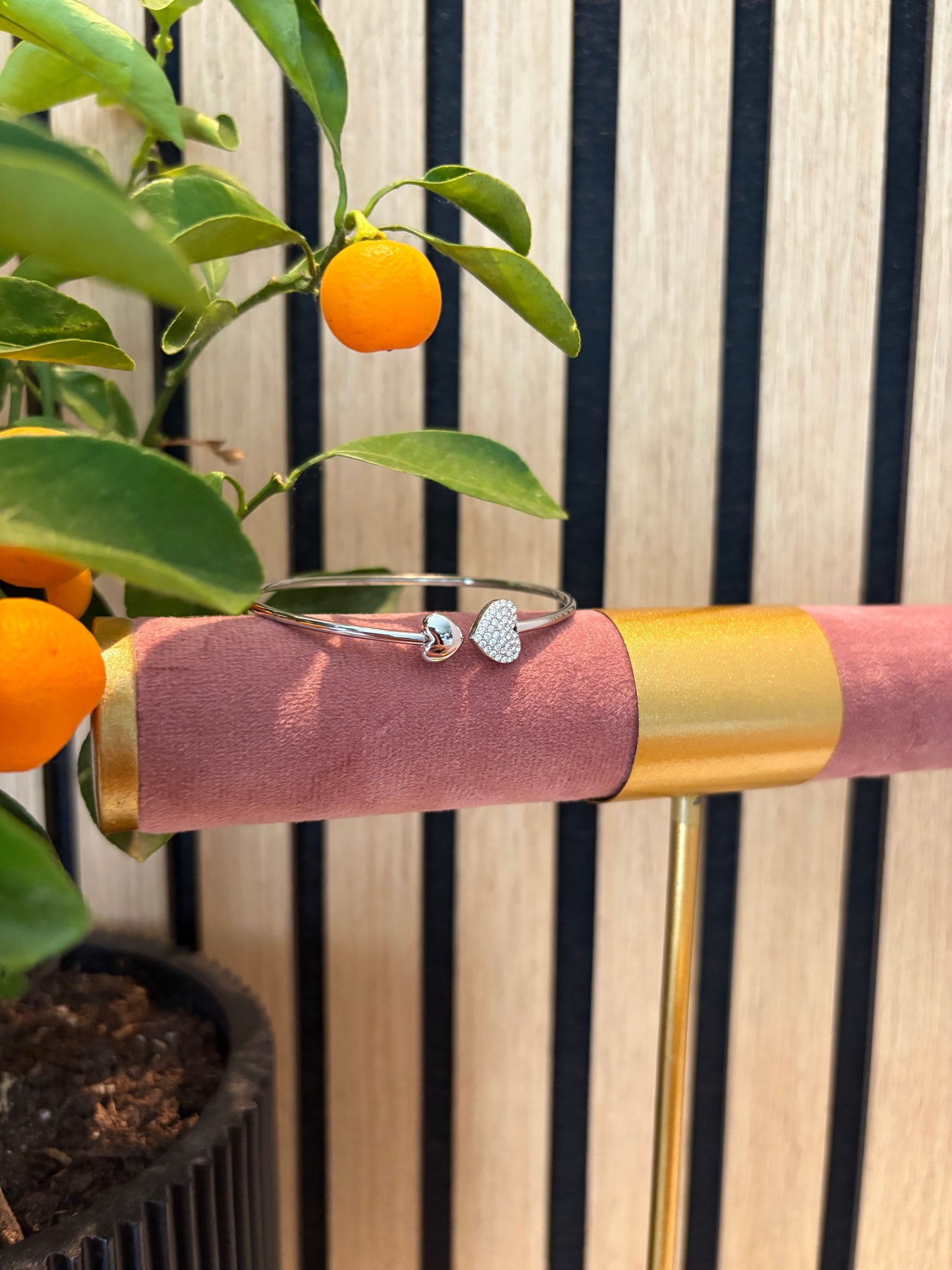 Heart to Handle armband zilverkleurig – open bangle met hartvormige uiteinden, modern design gepresenteerd op roze display.
