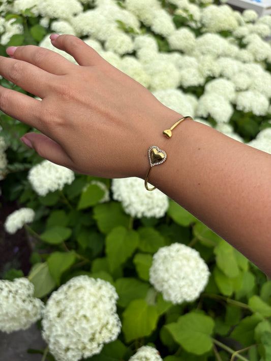 Gouden hartvormige damesarmband – Heart to Handle design gedragen om pols, stijlvolle accessoire bij zomerse outfit.