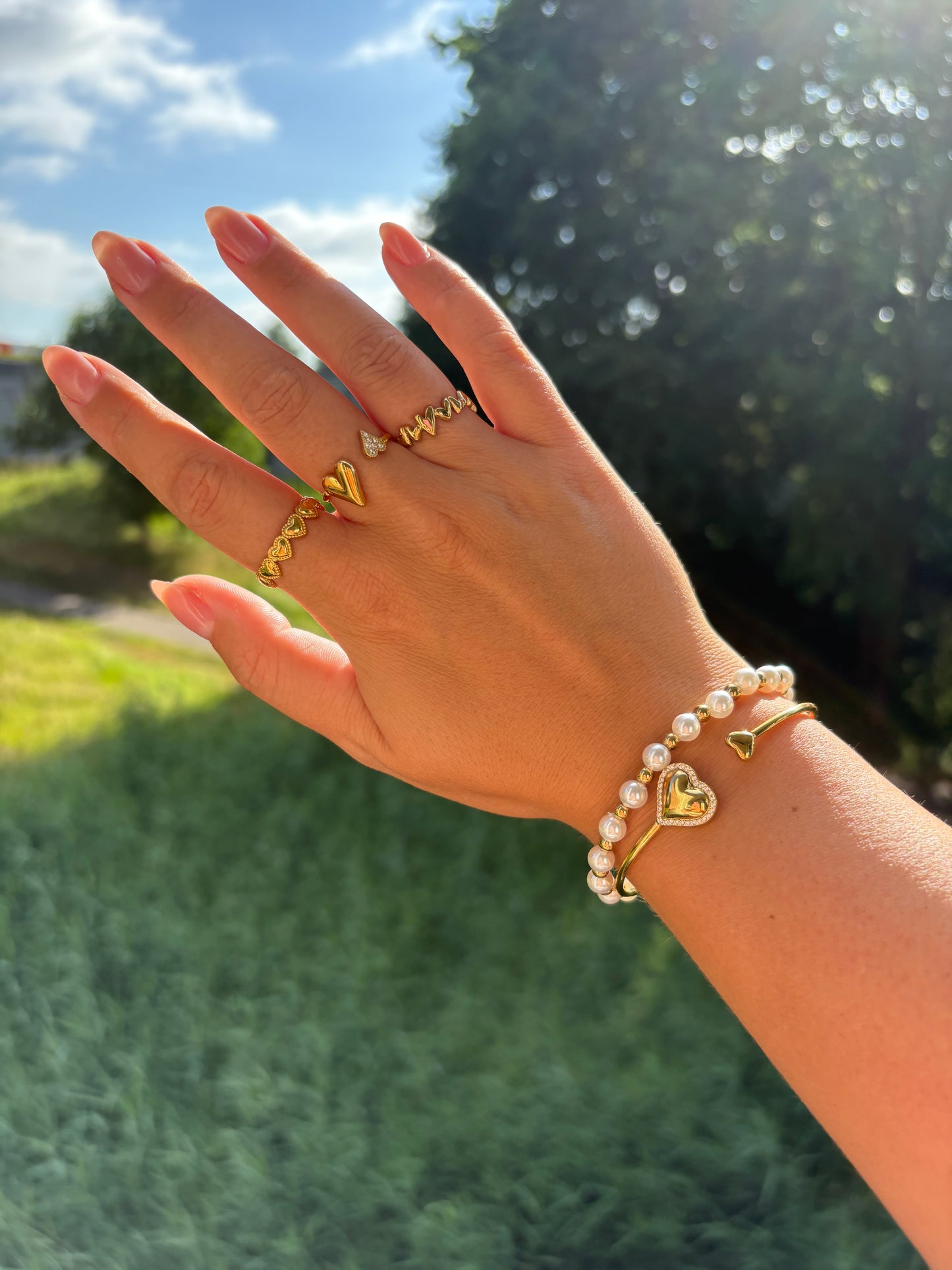 Set met gouden armband en parelarmband – Heart to Handle armband gecombineerd met statement sieraden, perfect voor zonnige zomerdagen.