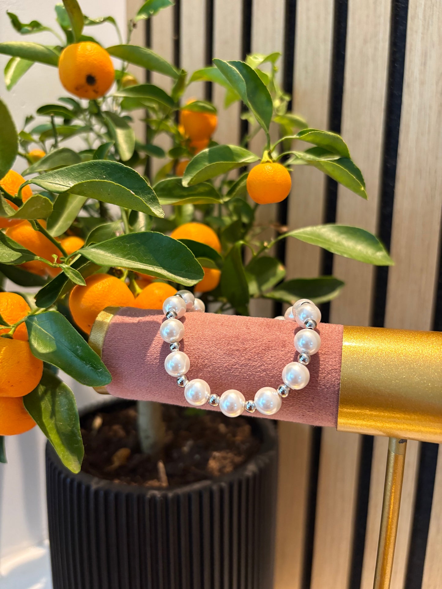 Zilveren parelarmband “Pearly Girly” met ronde glanzende kralen, elegant gepresenteerd op een display