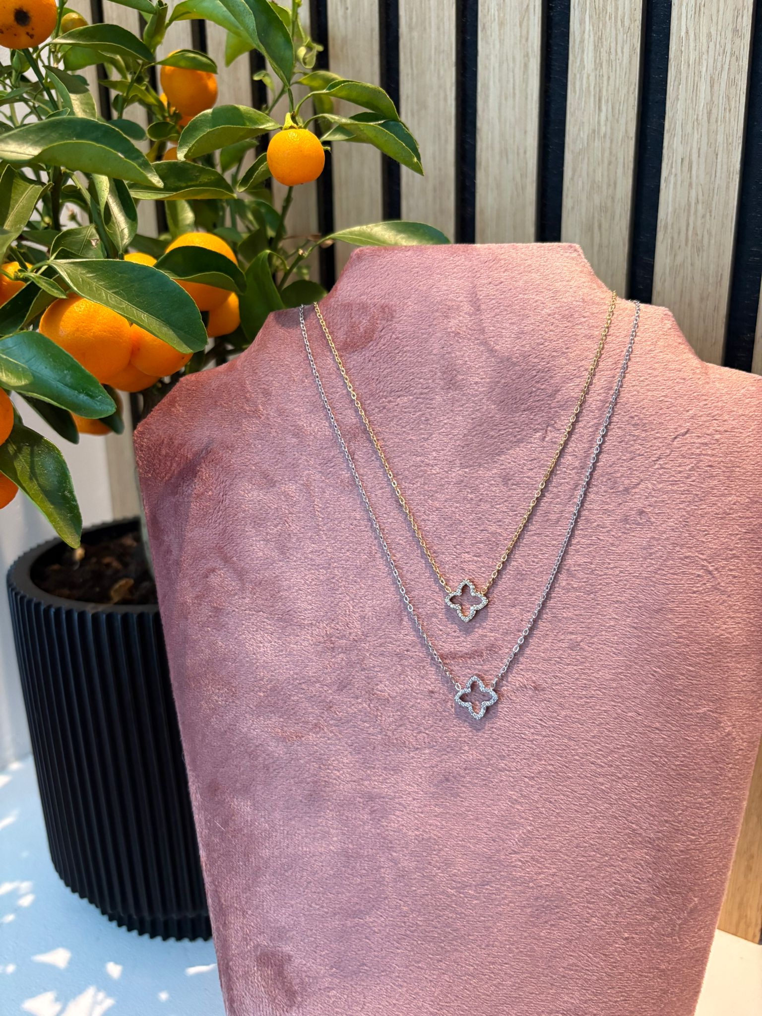 "Shine not sorry" ketting – Goud- en zilverkleurige schakelketting met klavervormige hanger op een roze fluwelen kettingdisplay